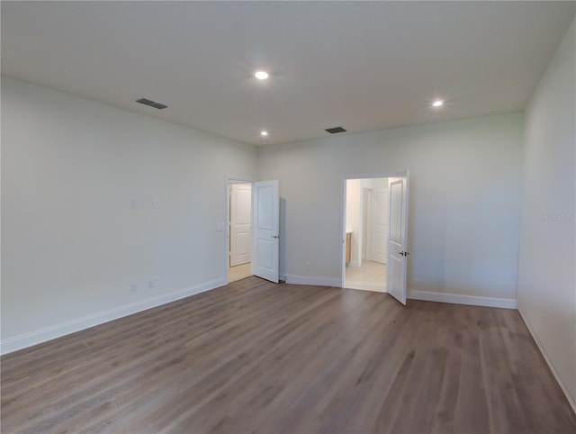 unfurnished bedroom with ensuite bathroom and light hardwood / wood-style floors