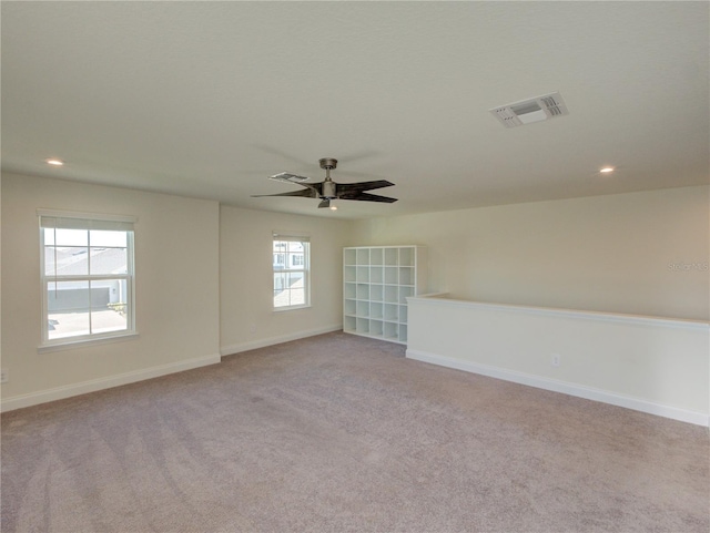 spare room with ceiling fan, plenty of natural light, and light colored carpet