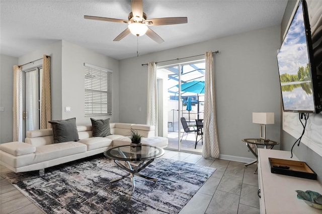 living room featuring ceiling fan, light tile patterned floors, and a textured ceiling