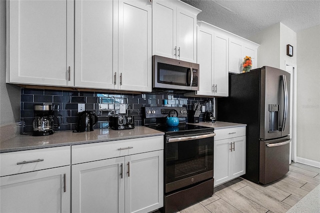 kitchen with white cabinetry, stainless steel appliances, backsplash, a textured ceiling, and light wood-type flooring