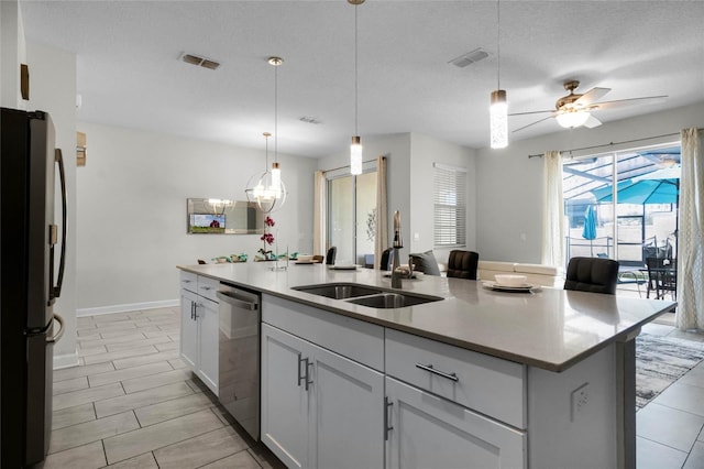 kitchen with a textured ceiling, stainless steel appliances, a kitchen island with sink, ceiling fan, and white cabinetry