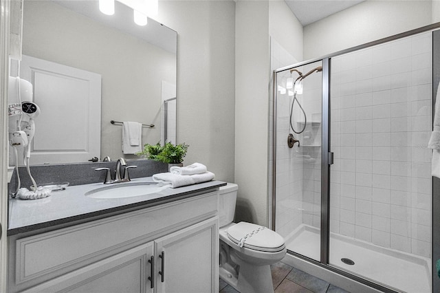 bathroom featuring tile patterned flooring, vanity, an enclosed shower, and toilet