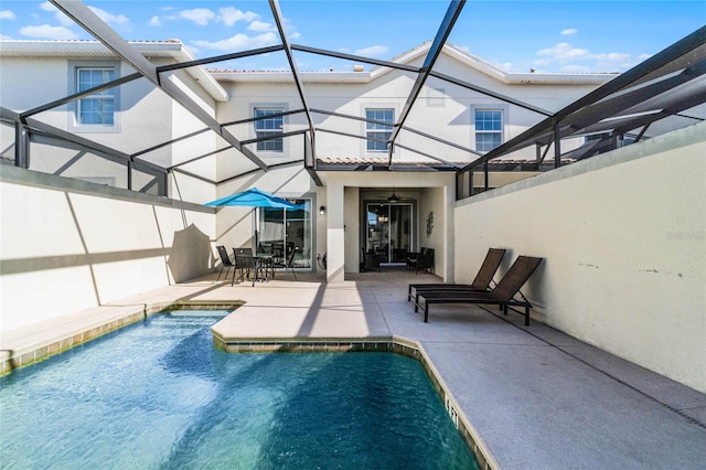 view of swimming pool featuring a patio, glass enclosure, and ceiling fan