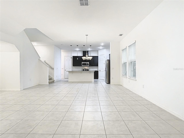 unfurnished living room featuring light tile patterned flooring and a chandelier