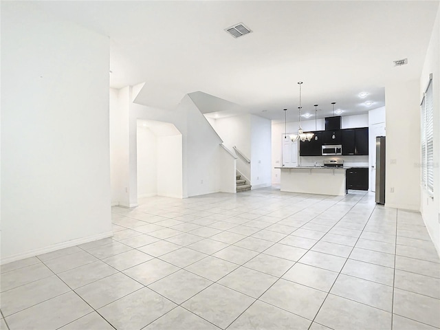 unfurnished living room featuring an inviting chandelier and light tile patterned flooring