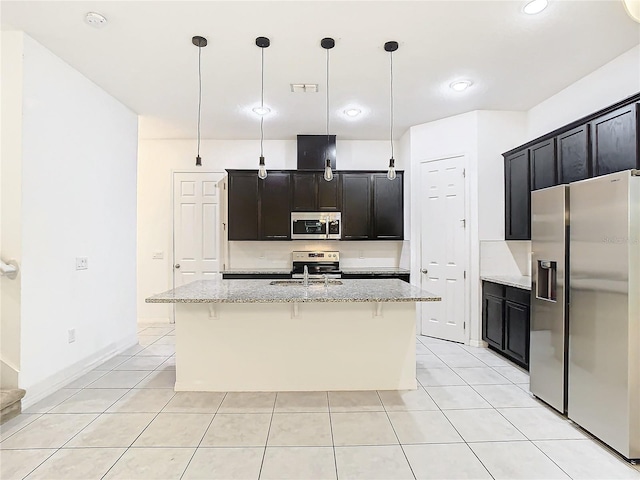 kitchen featuring hanging light fixtures, light stone countertops, light tile patterned floors, an island with sink, and appliances with stainless steel finishes