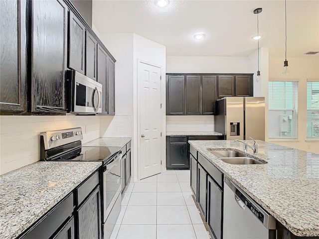 kitchen featuring appliances with stainless steel finishes, light stone counters, sink, hanging light fixtures, and light tile patterned flooring