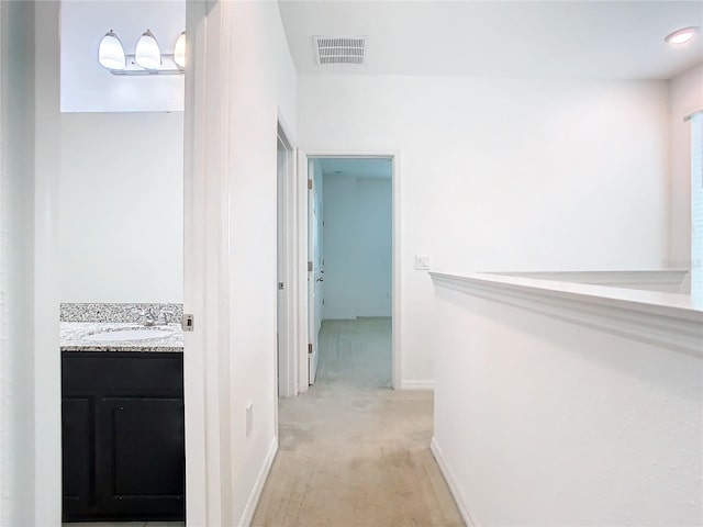 hallway featuring light colored carpet and sink