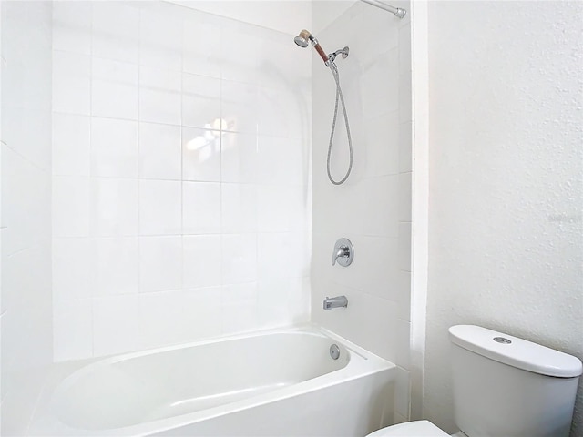 bathroom featuring tiled shower / bath combo and toilet