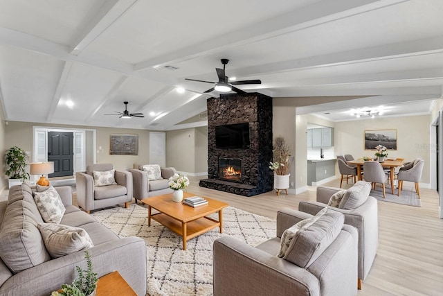 living room with lofted ceiling with beams, a fireplace, ceiling fan, and light hardwood / wood-style floors