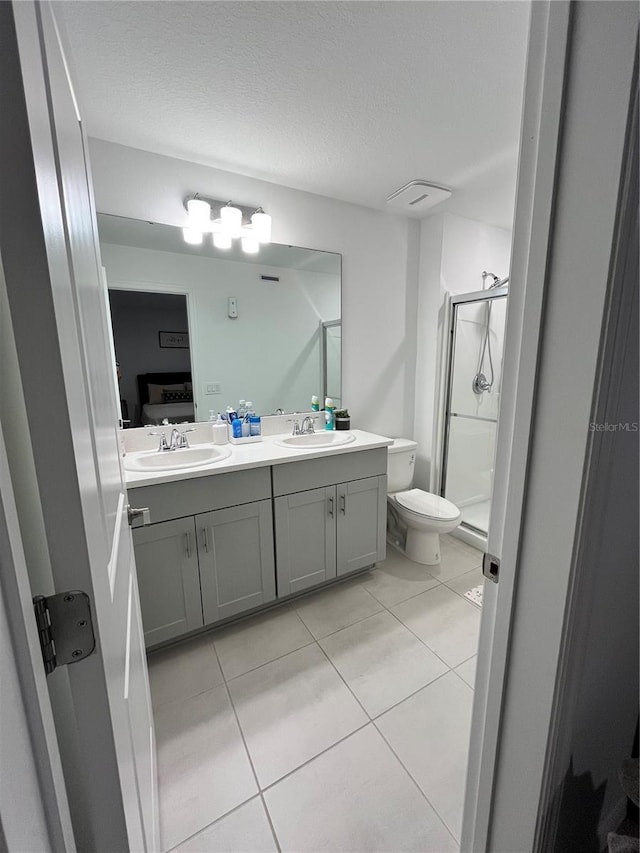 bathroom featuring vanity, a shower with door, tile patterned floors, toilet, and a textured ceiling