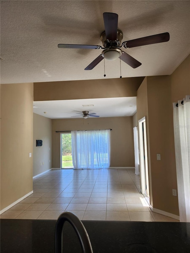 unfurnished room with ceiling fan, light tile patterned floors, and a textured ceiling