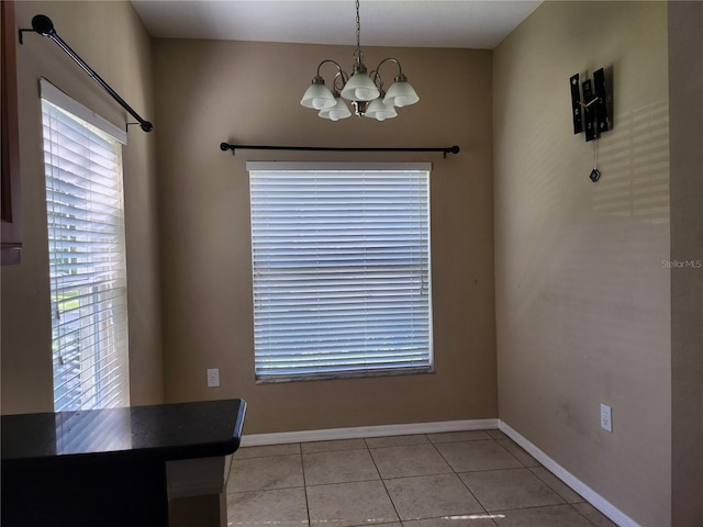 unfurnished dining area featuring a notable chandelier, plenty of natural light, and light tile patterned floors