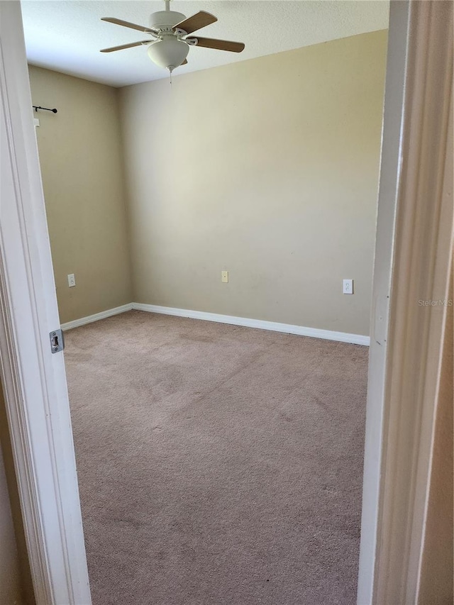 empty room featuring ceiling fan and light colored carpet