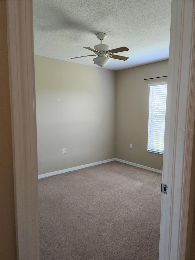 empty room with light carpet, ceiling fan, and a textured ceiling