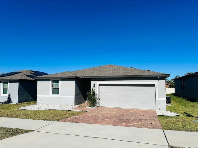 view of front of property with central AC, a front lawn, and a garage