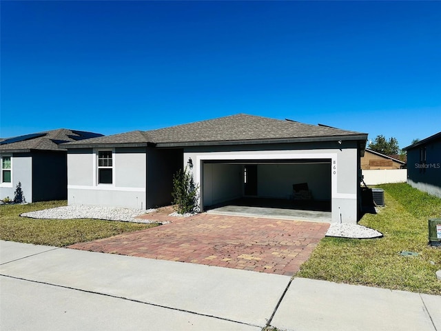 view of front facade with a front yard, a garage, and cooling unit