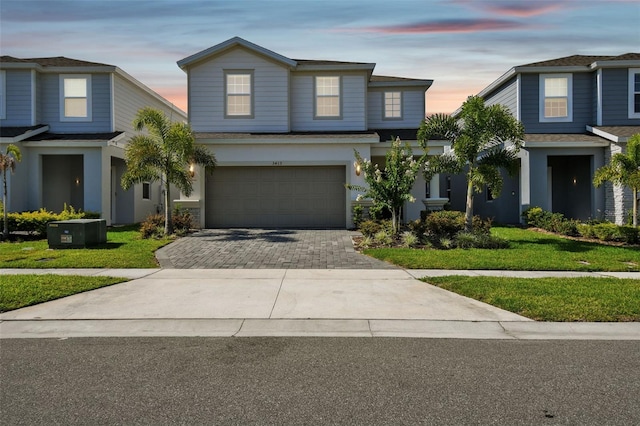 view of front of house with a garage, a yard, and central AC