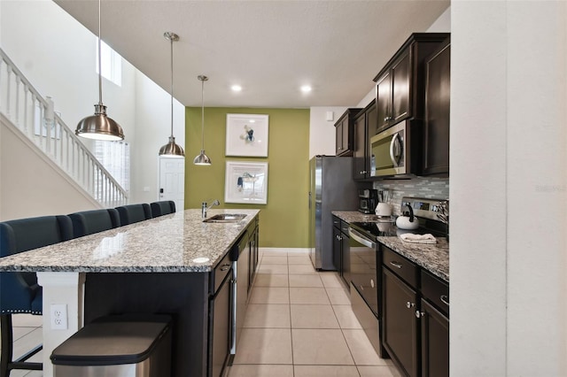 kitchen with backsplash, a breakfast bar, a kitchen island with sink, and appliances with stainless steel finishes