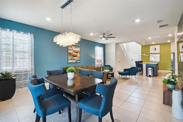 tiled dining space featuring ceiling fan with notable chandelier