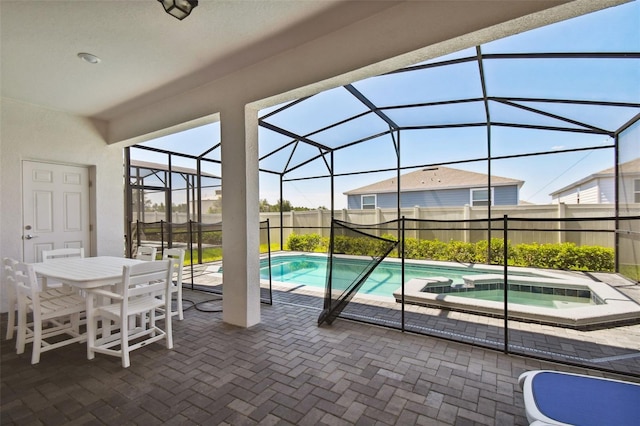 view of swimming pool with glass enclosure, an in ground hot tub, and a patio