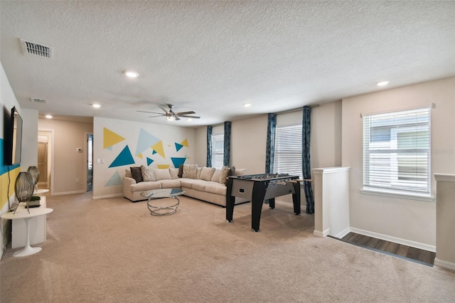 carpeted living room featuring ceiling fan and a textured ceiling