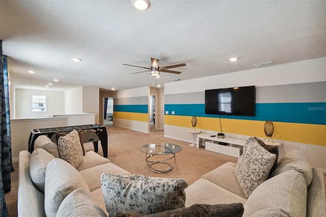 carpeted living room featuring ceiling fan and a textured ceiling