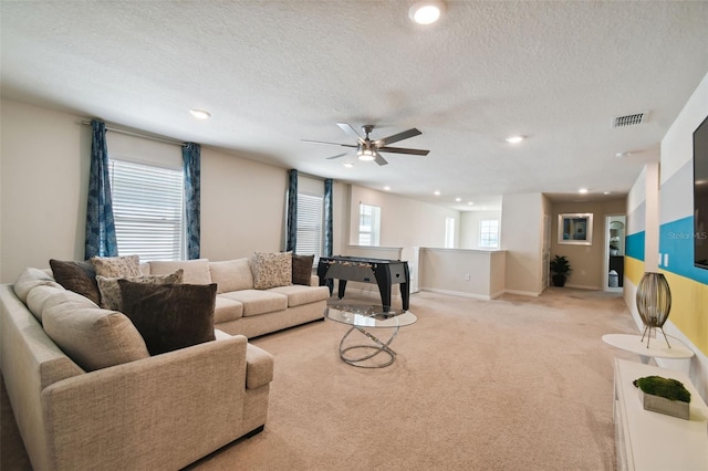 living room with ceiling fan, light colored carpet, a textured ceiling, and a wealth of natural light