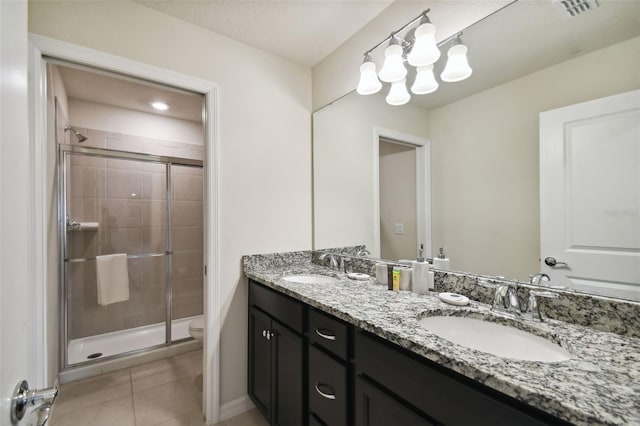 bathroom with tile patterned floors, vanity, toilet, and a shower with door