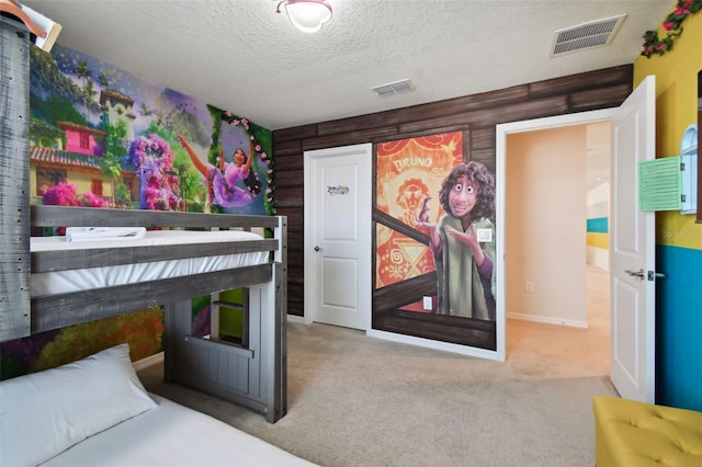 bedroom with carpet flooring, a textured ceiling, and wooden walls