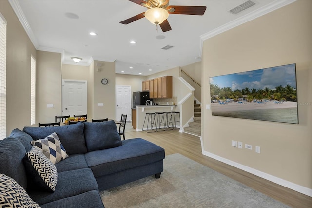 living room featuring crown molding, light hardwood / wood-style flooring, and ceiling fan