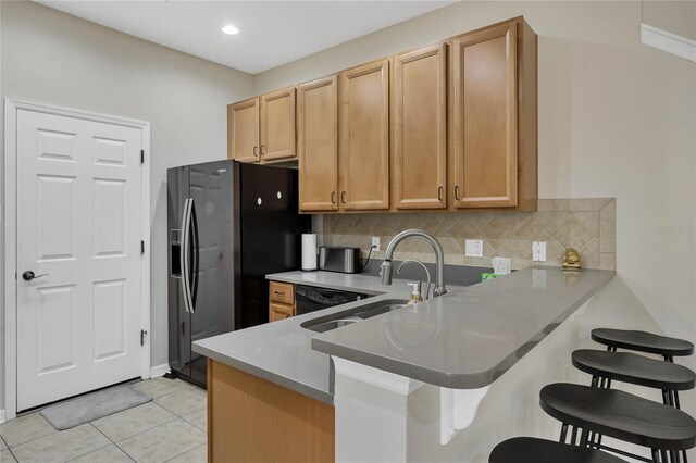 kitchen featuring sink, tasteful backsplash, light tile patterned flooring, kitchen peninsula, and a breakfast bar area