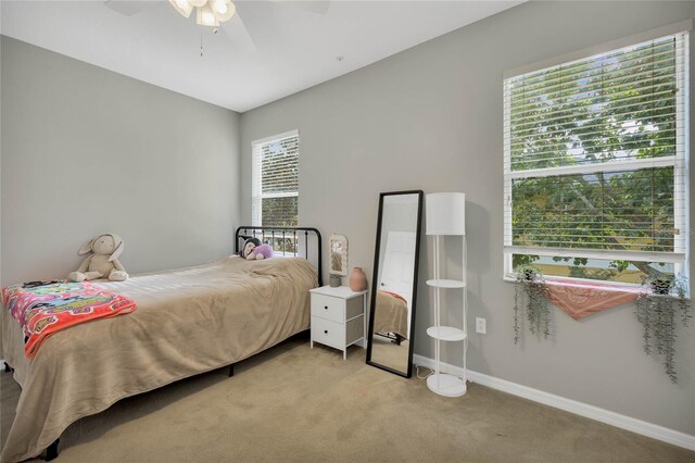 bedroom featuring ceiling fan, light carpet, and multiple windows