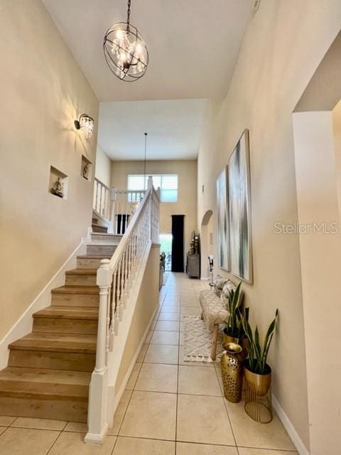 stairway featuring tile patterned flooring and a notable chandelier