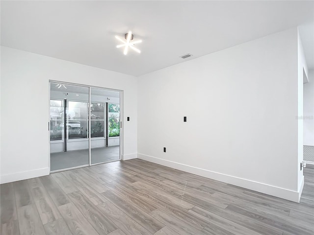 spare room featuring light hardwood / wood-style flooring and a chandelier