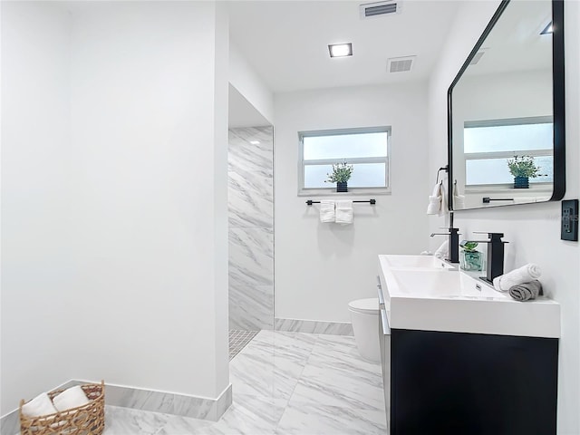 bathroom with tiled shower, vanity, and toilet