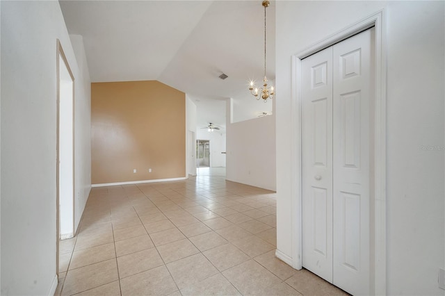 unfurnished room featuring ceiling fan with notable chandelier, light tile patterned flooring, and vaulted ceiling