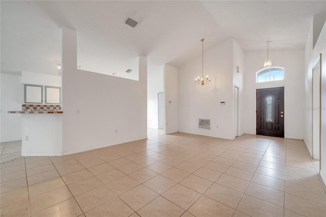 entrance foyer featuring light tile patterned flooring, high vaulted ceiling, and a chandelier