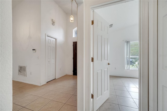 hallway featuring light tile patterned flooring and a towering ceiling