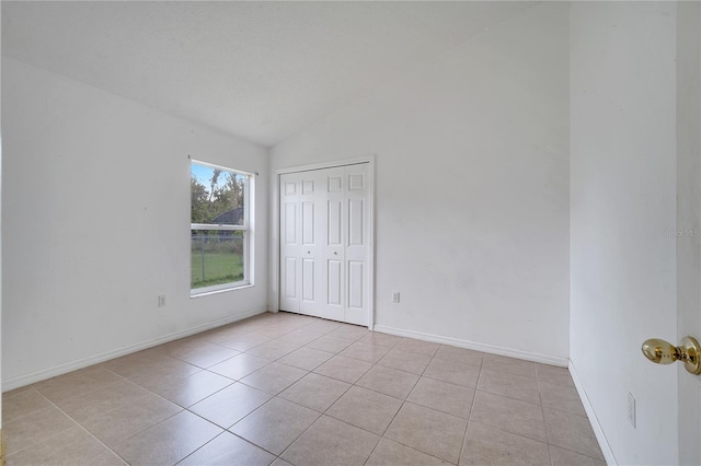 spare room with lofted ceiling and light tile patterned floors