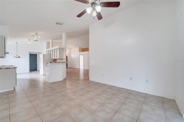 tiled empty room featuring ceiling fan and vaulted ceiling