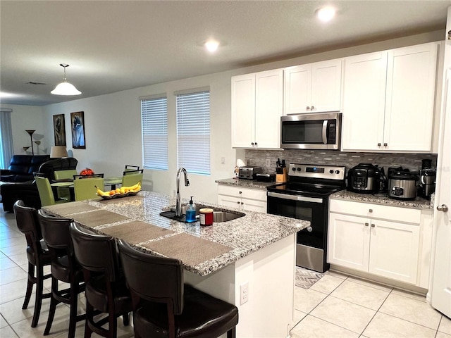 kitchen with white cabinets, stainless steel appliances, a center island with sink, and sink