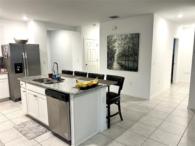 kitchen with white cabinets, sink, light stone countertops, an island with sink, and appliances with stainless steel finishes