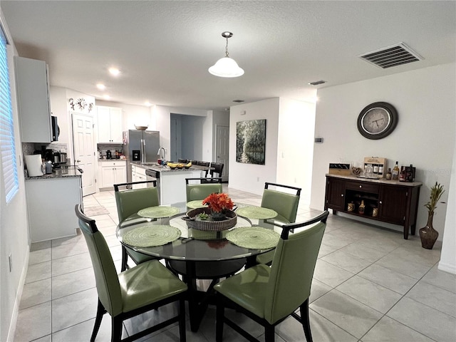 dining room with a textured ceiling, light tile patterned floors, and sink