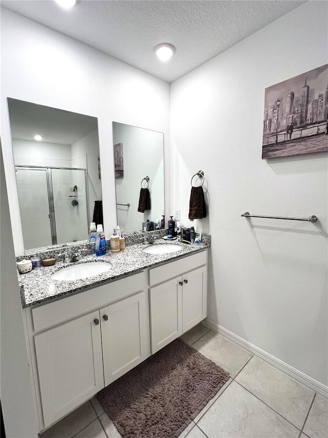 bathroom featuring a shower with door, vanity, a textured ceiling, and tile patterned flooring