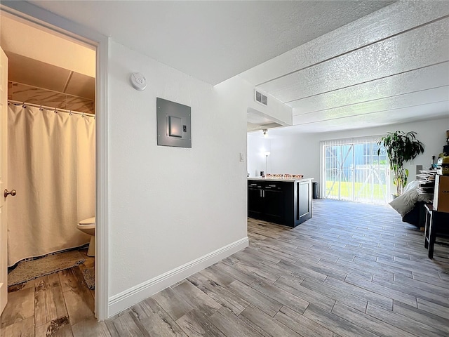 hallway with electric panel, light hardwood / wood-style flooring, and a textured ceiling