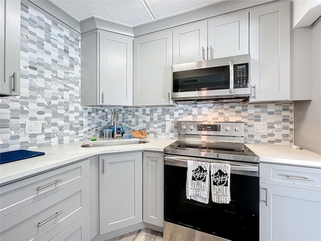 kitchen featuring backsplash, sink, light hardwood / wood-style flooring, light stone countertops, and stainless steel appliances