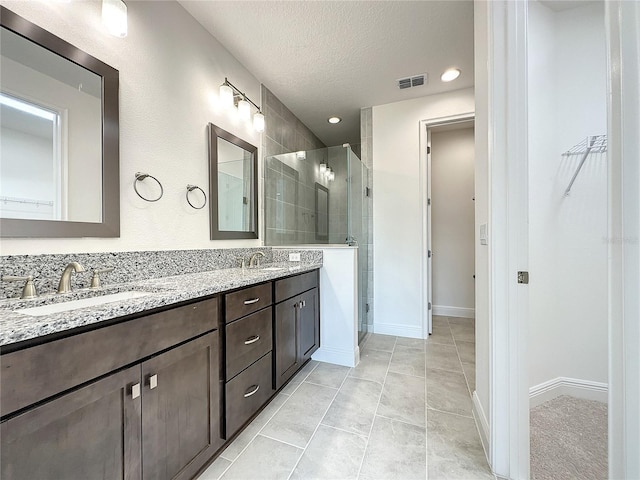 bathroom with vanity, a textured ceiling, tile patterned floors, and walk in shower