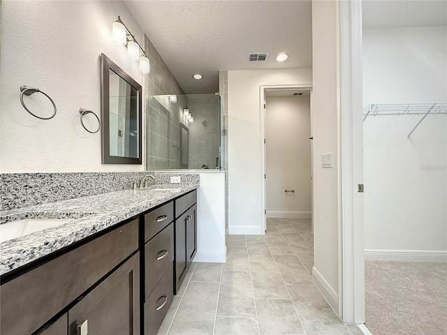 bathroom featuring a textured ceiling, vanity, tile patterned floors, and an enclosed shower