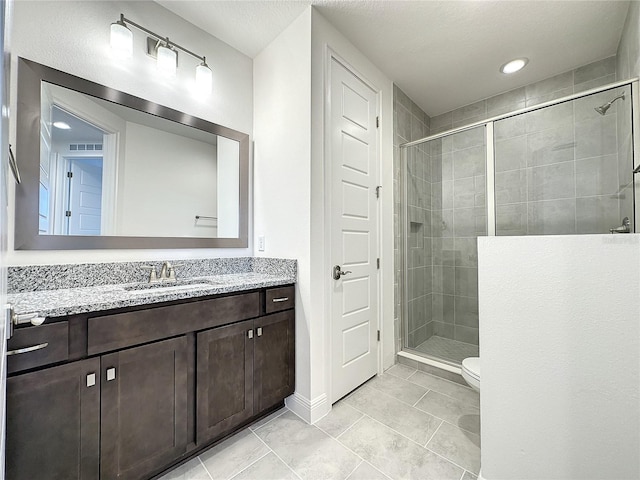 bathroom with tile patterned floors, toilet, vanity, and walk in shower